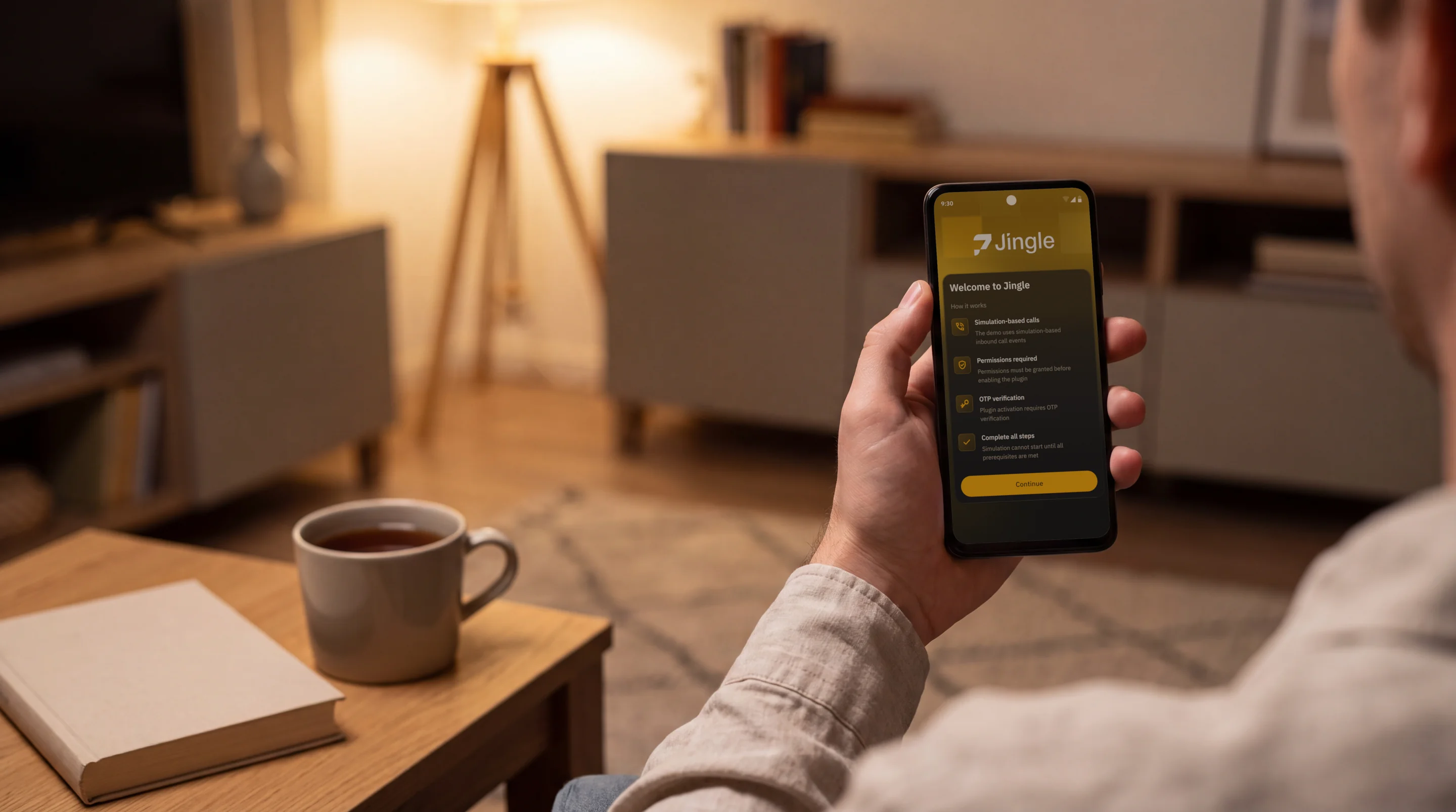 A person in an armchair at home holding an Android phone that shows the Welcome to Jingle screen explaining how the demo works