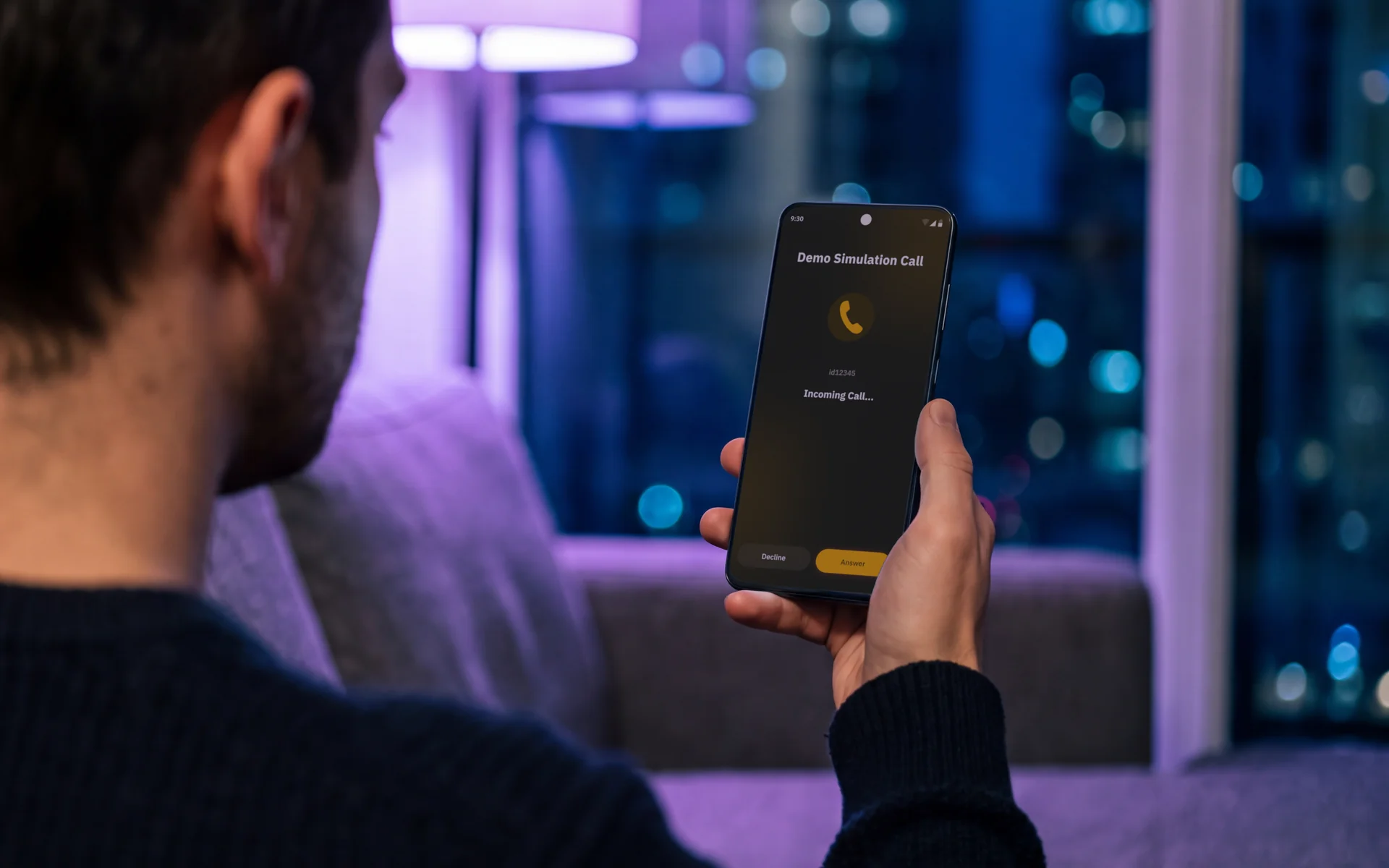 A person on a sofa at night holding an Android phone showing an incoming Jingle demo call with Answer and Decline buttons