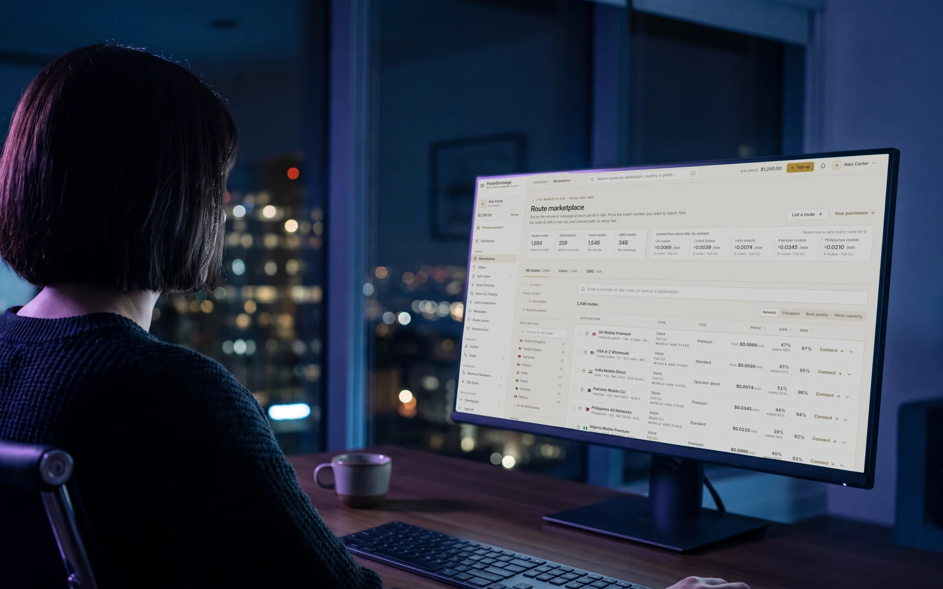 A wholesale voice buyer at night reviewing the PacketExchange route marketplace on a large monitor, with live routes, prices, ASR and caller ID type